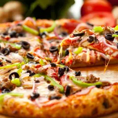 Gotowa pizza z ciągnącym serem, oliwkami, papryką i cebulą na drewnianej desce.