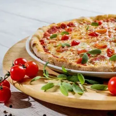 Pizza z pomidorkami koktajlowymi i bazylią na drewnianej desce.
