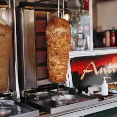 Dwa pionowe rożna z mięsem do kebaba na tle budki z napisem "Antalya".