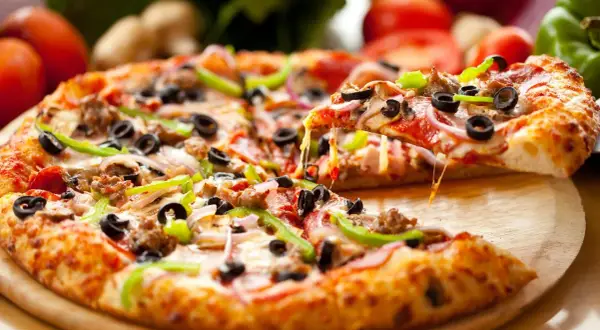 Gotowa pizza z ciągnącym serem, oliwkami, papryką i cebulą na drewnianej desce.