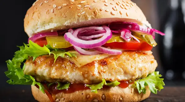 Domowy hamburger z kurczakiem, serem, sałatą, pomidorem, ogórkiem i czerwoną cebulą.
