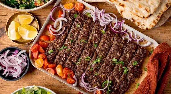 Kebab z mięsa mielonego, pomidorkami, cebulą i pieczywem.